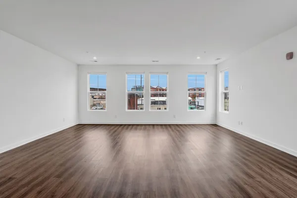 a view of an empty room with window and wooden floor