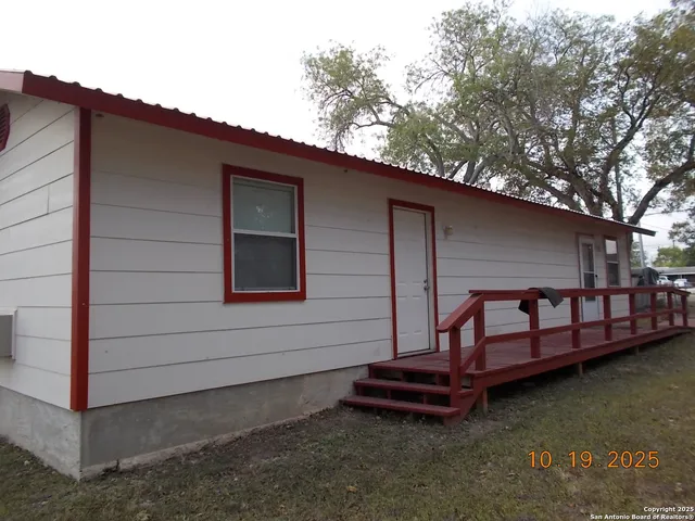 a backyard of a house with large trees and outdoor seating