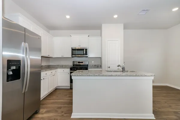 a kitchen with stainless steel appliances granite countertop a sink a stove a refrigerator with white cabinets