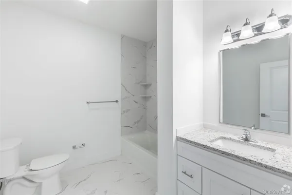 a bathroom with a granite countertop sink a toilet and shower