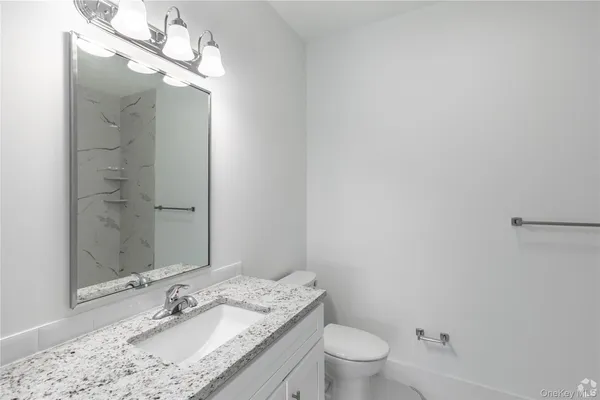 a bathroom with a granite countertop sink a toilet and shower