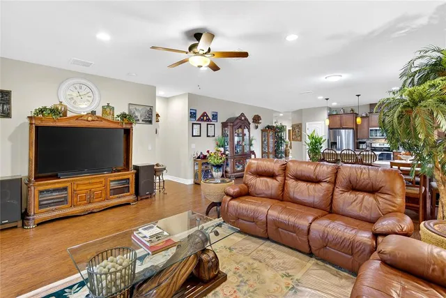 a kitchen with stainless steel appliances kitchen island granite countertop a refrigerator a stove a sink and a dining table with wooden floor