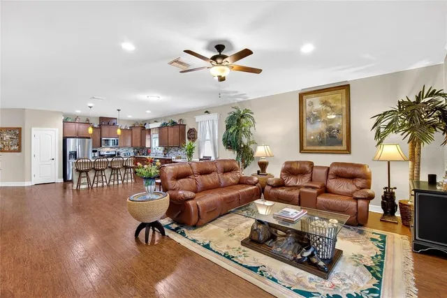 a kitchen with stainless steel appliances granite countertop a kitchen island a stove a sink a oven a dining table and chairs with wooden floor