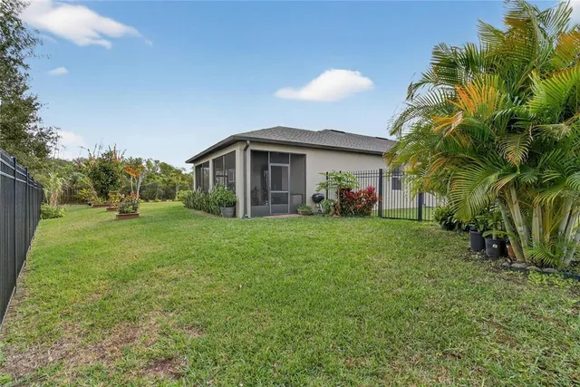 a view of a backyard with table and chairs potted plants and large tree