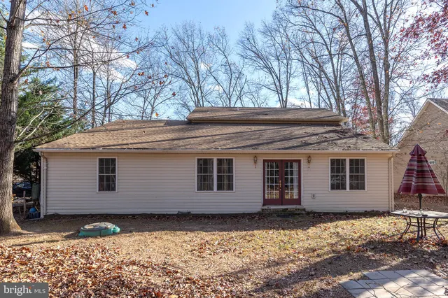 a backyard of a house with large trees and wooden fence