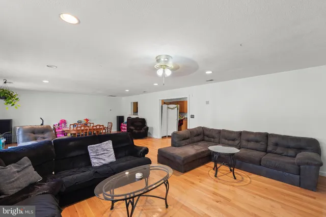a living room with furniture and a dining table with wooden floor
