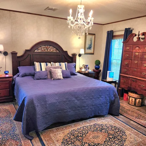 a bedroom with a bed a dresser and a chandelier