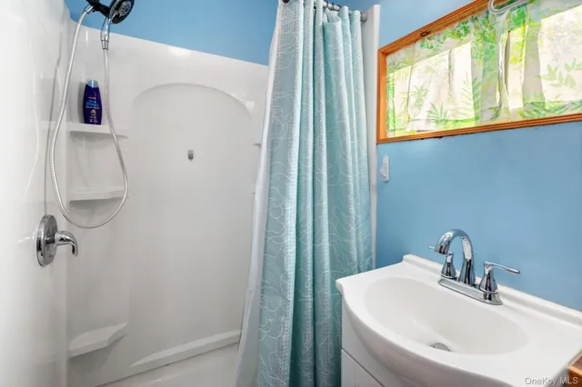 a bathroom with a sink a window and shower curtain
