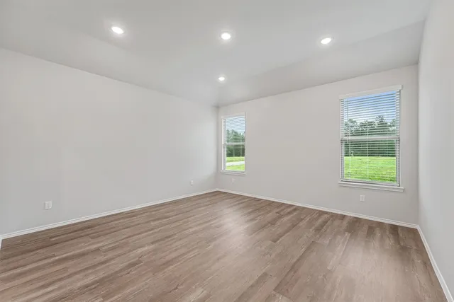 an empty room with wooden floor and windows