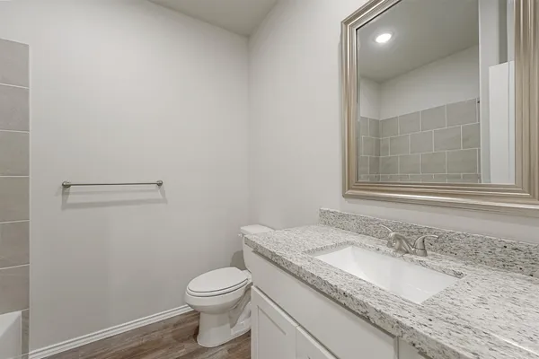 a bathroom with a granite countertop sink a toilet and a mirror