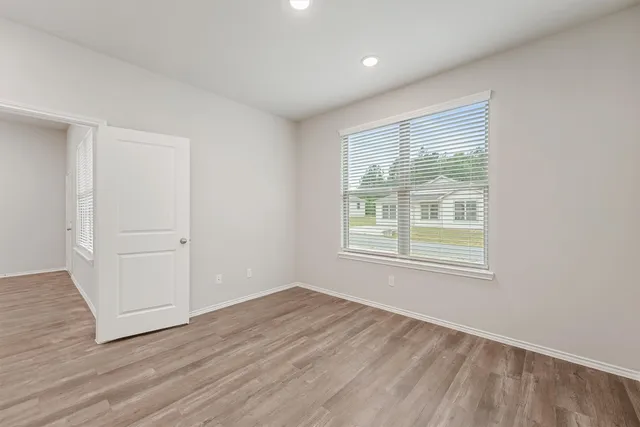 an empty room with wooden floor and windows