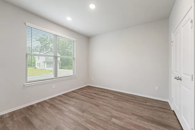 an empty room with wooden floor and windows