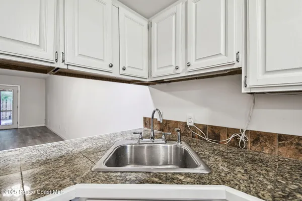 a kitchen with granite countertop white cabinets and a stove top oven