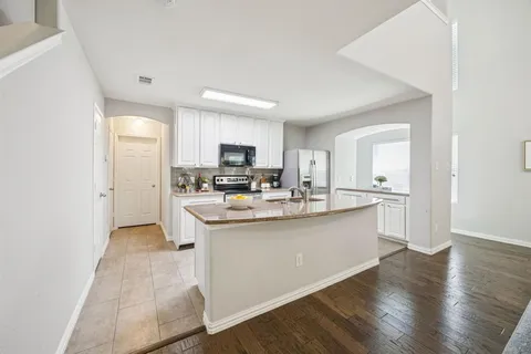 a kitchen with stainless steel appliances a sink a stove a refrigerator cabinets and a window