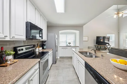 a large kitchen with a stove top oven a sink a counter space and cabinets