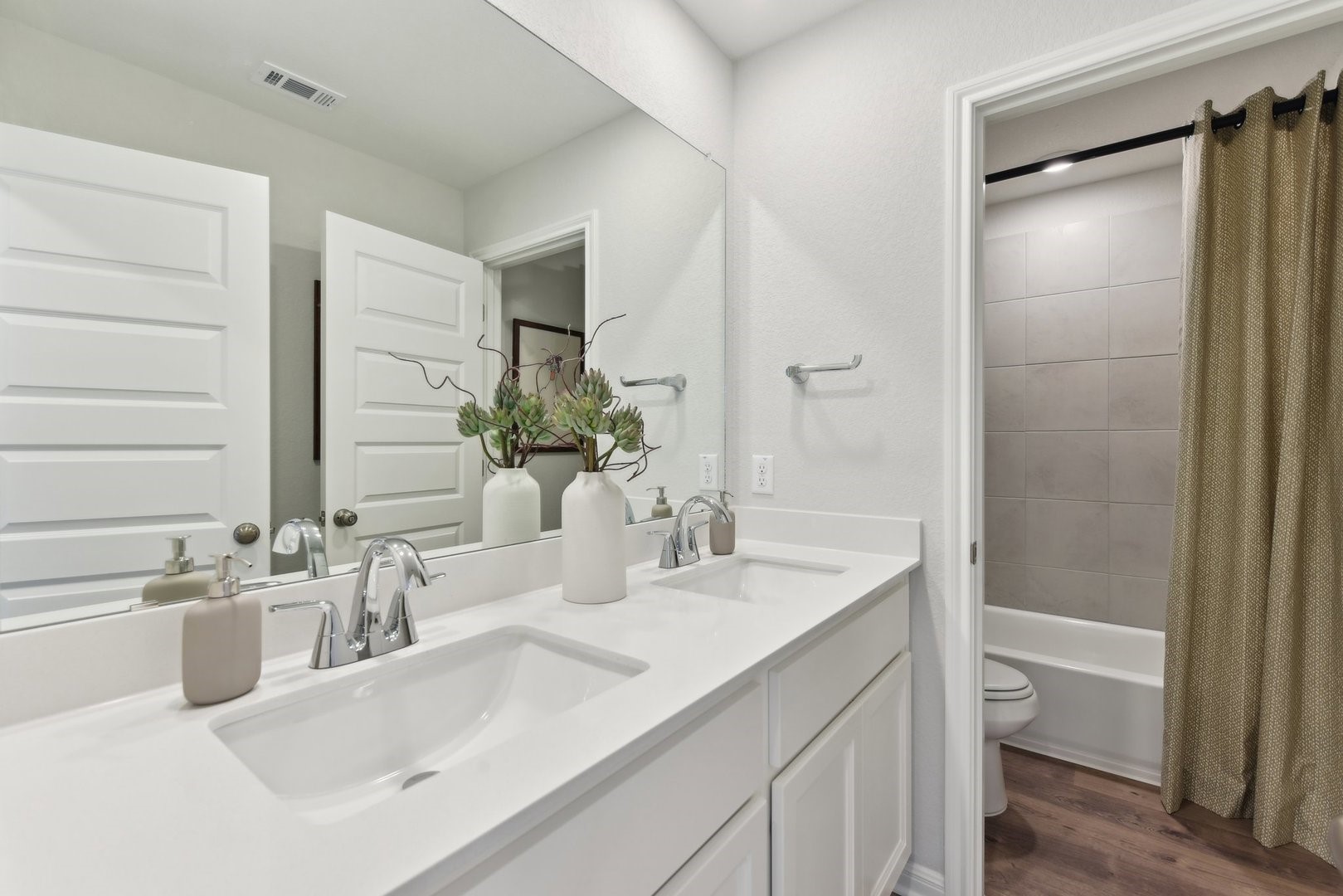 216 Firefox Way Jarrell, TX 76537 - Photo 14 of 17 A spacious double vanity matches perfectly with the clean tiled tub surround and rich wood-style flooring.