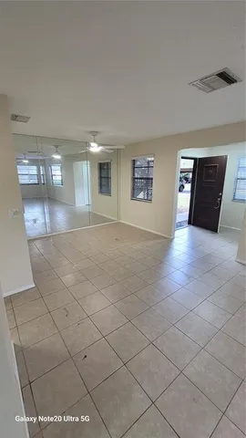 a view of an empty room with windows and a kitchen