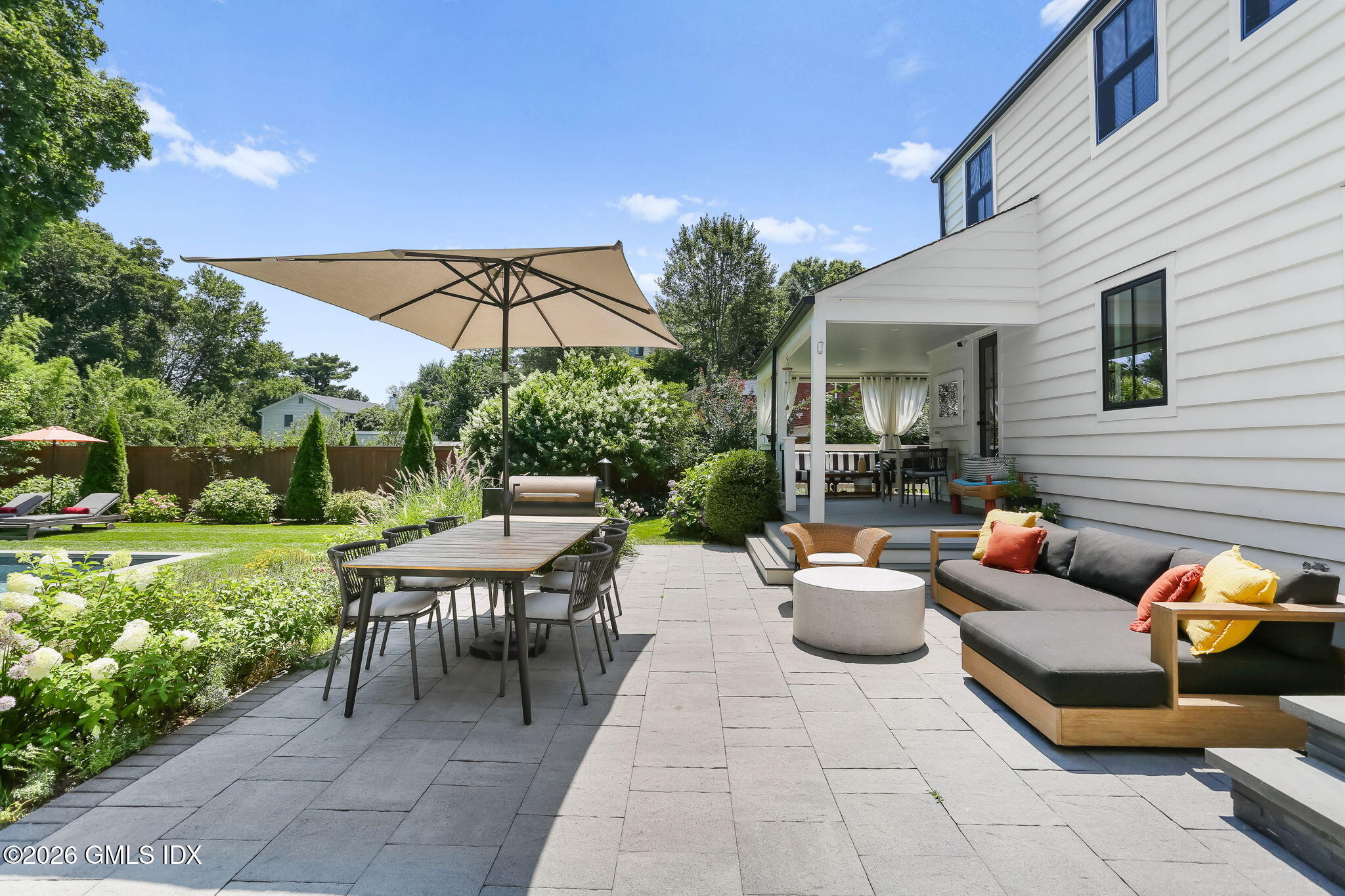 39 Indian Field Road Greenwich, CT 06830 - Photo 5 of 8 a view of a patio with couches table and chairs under an umbrella
