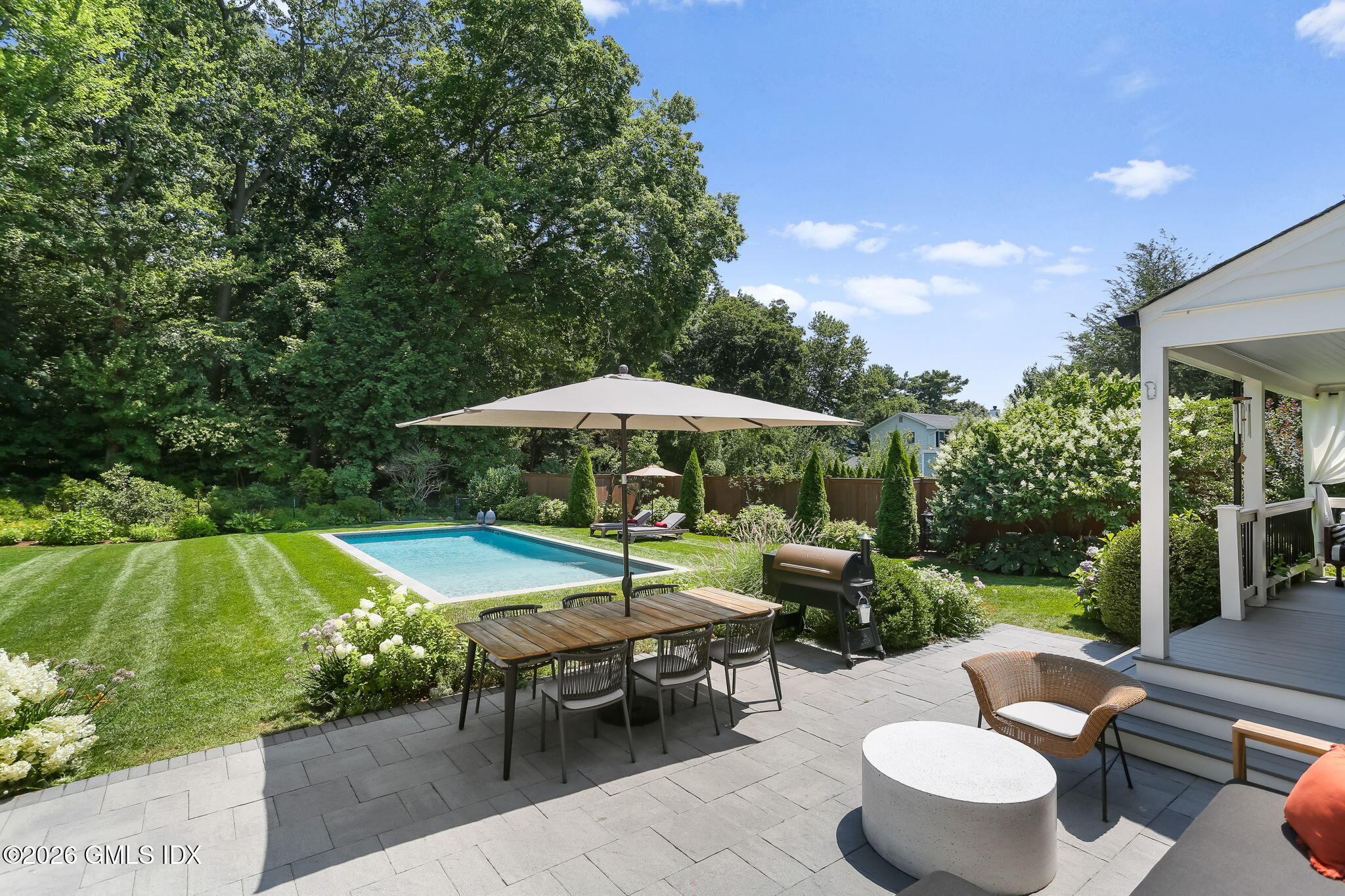 39 Indian Field Road Greenwich, CT 06830 - Photo 6 of 8 a view of a patio with chairs and table under an umbrella