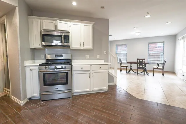 a large white kitchen with stainless steel appliances granite countertop a stove and a wooden floors