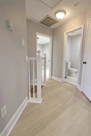 a view of an empty room with wooden floor and a bathroom