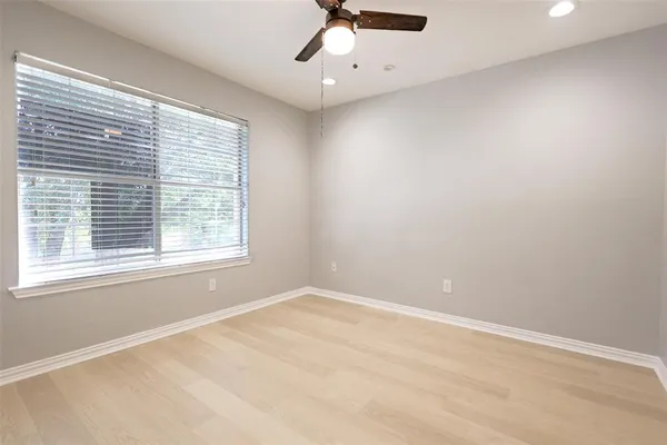 an empty room with a window and a fan