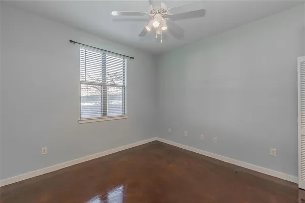 an empty room with wooden floor and ceiling fan
