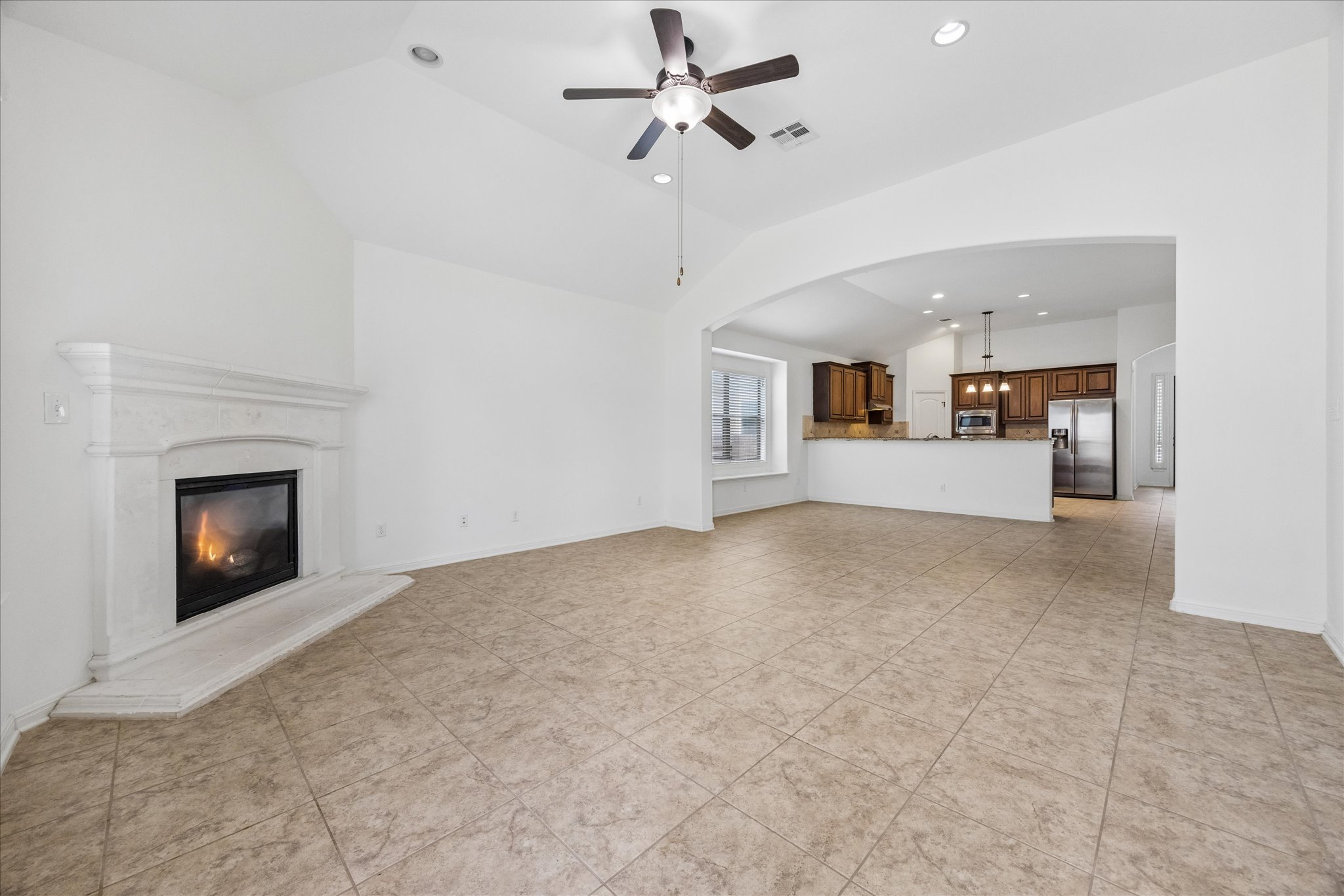14304 Senia Bend Austin, TX 78738 - Photo 6 of 15 A well-lit living area with a fireplace seamlessly flows into dining area and spacious kitchen.