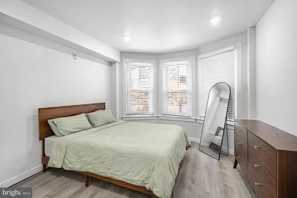 a bedroom with a bed chair and windows