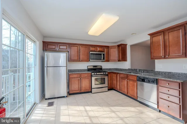 a large kitchen with stainless steel appliances granite countertop a refrigerator and a stove top oven