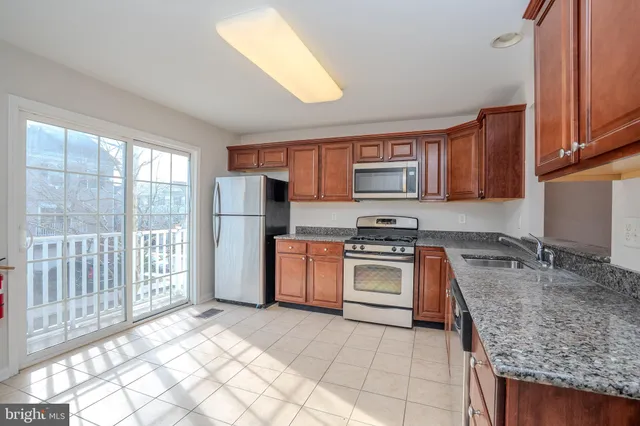 a kitchen with stainless steel appliances granite countertop a stove top oven a sink and a refrigerator