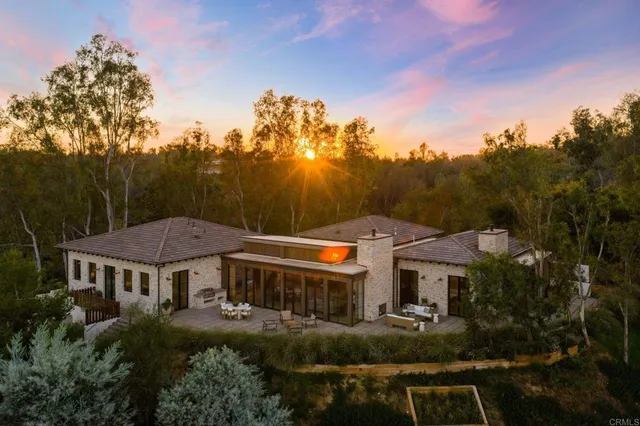 a view of a big house with a big yard plants and large trees