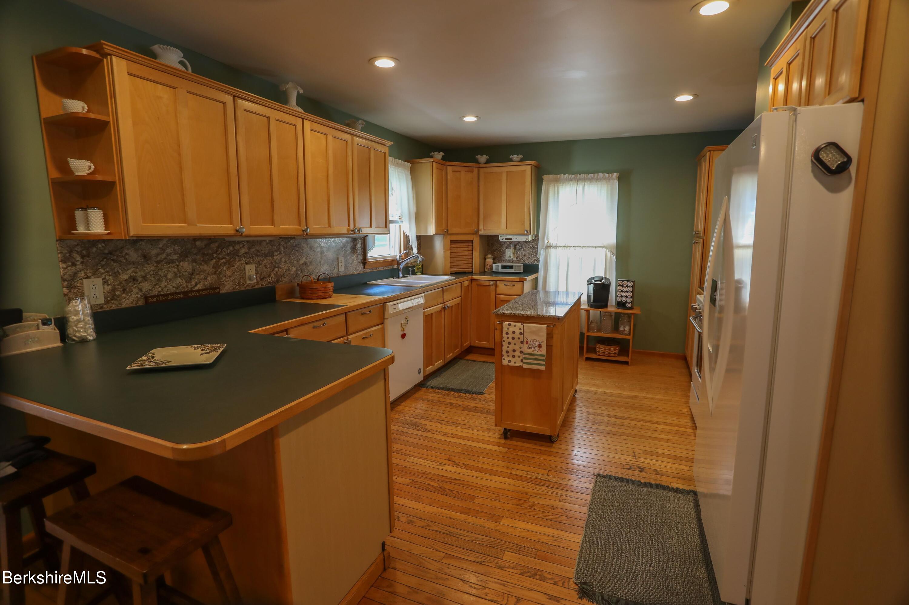 792 Middle Road Clarksburg, MA 01247 - Photo 10 of 40 a kitchen with stainless steel appliances granite countertop a refrigerator a sink dishwasher a stove and a dining table with wooden floor