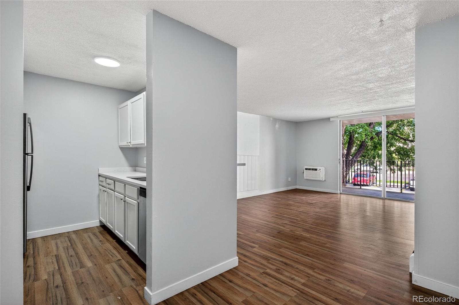 2281 South Vaughn Way Aurora, CO 80014 - Photo 1 of 23 a kitchen with wooden floors and white cabinets