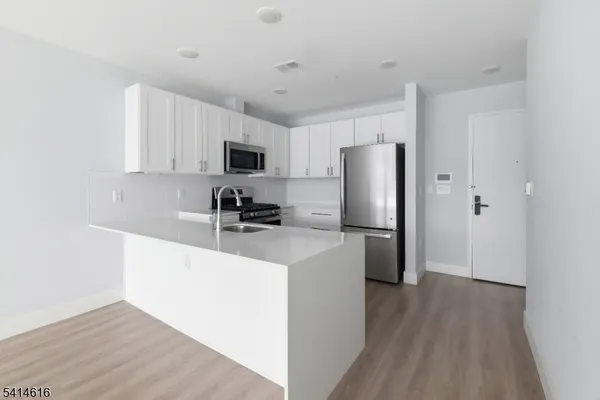 a kitchen with a refrigerator a stove top oven a sink and dishwasher with wooden floor