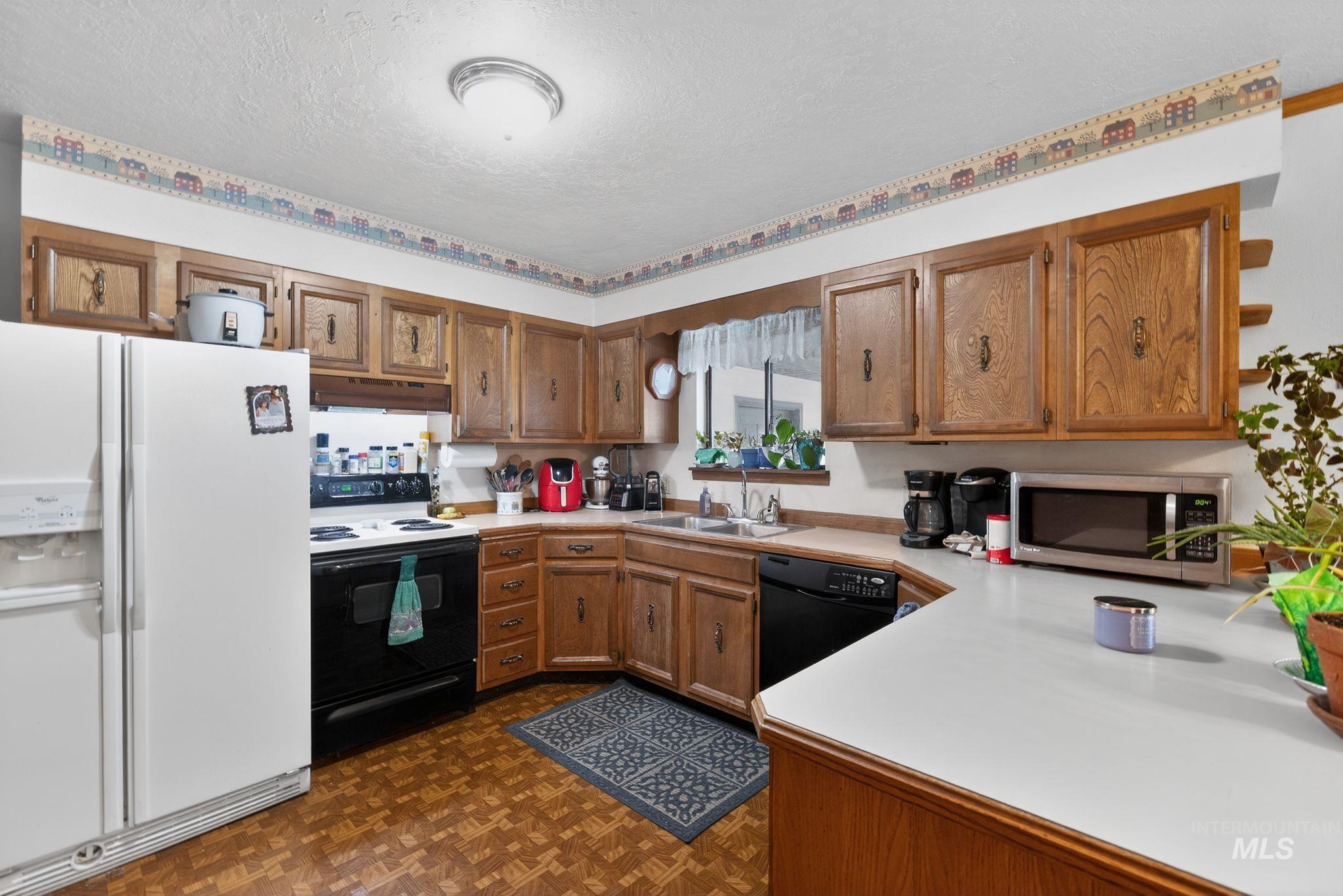 1055 South Adell Street Filer, ID 83328 - Photo 11 of 28 Kitchen featuring white fridge with ice dispenser, light countertops, brown cabinetry, range with electric stovetop, and a textured ceiling