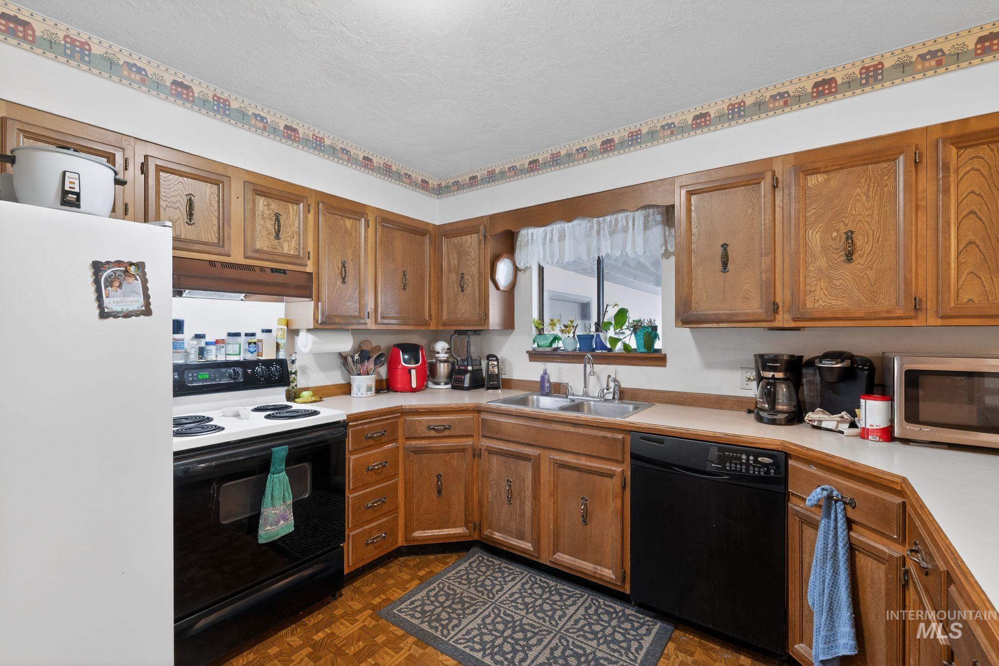 1055 South Adell Street Filer, ID 83328 - Photo 12 of 28 Kitchen with freestanding refrigerator, range with electric cooktop, light countertops, black dishwasher, and brown cabinetry
