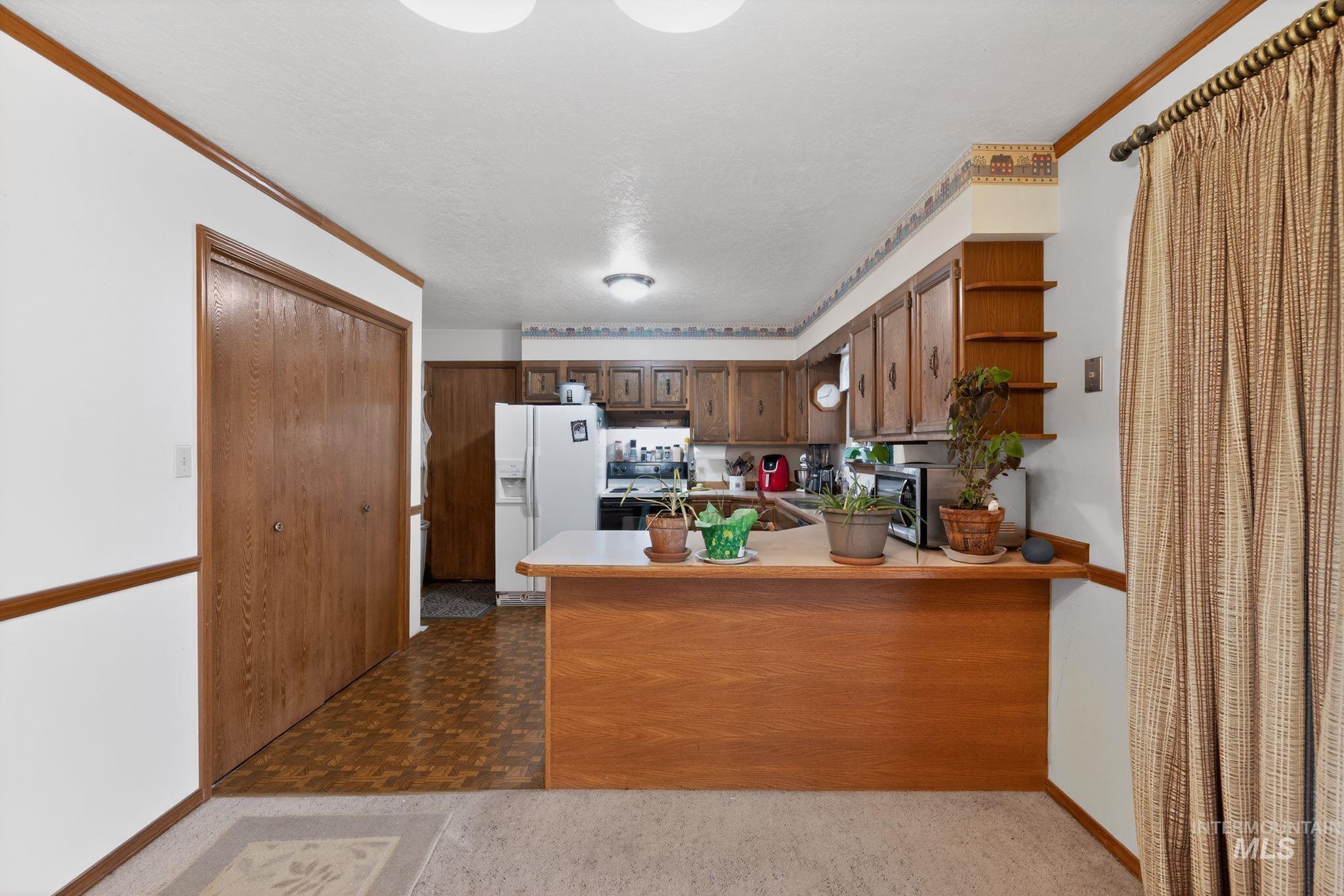 1055 South Adell Street Filer, ID 83328 - Photo 15 of 28 Kitchen featuring light countertops, white refrigerator with ice dispenser, a peninsula, stove, and dark flooring