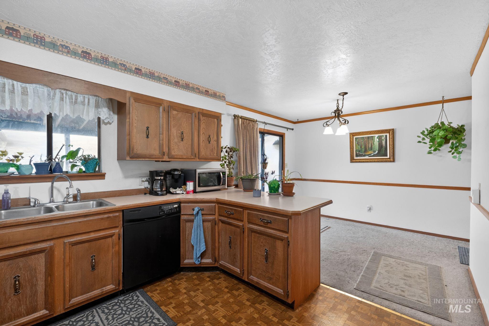 1055 South Adell Street Filer, ID 83328 - Photo 16 of 28 Kitchen with brown cabinetry, black dishwasher, a peninsula, a textured ceiling, and decorative light fixtures