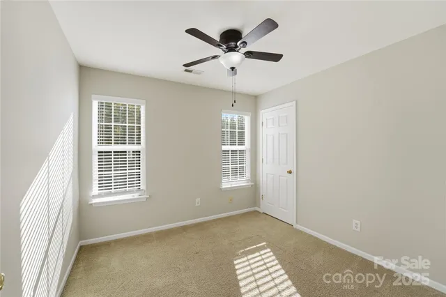 an empty room with windows and ceiling fan