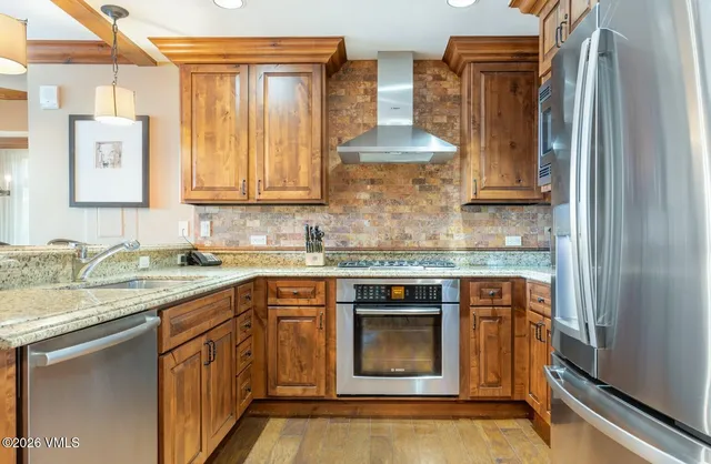 a kitchen with stainless steel appliances granite countertop a stove a sink and a refrigerator