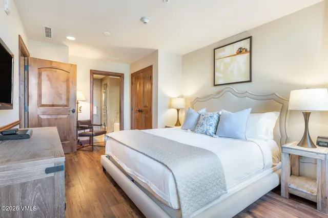 a spacious bedroom with a bed and wooden floor