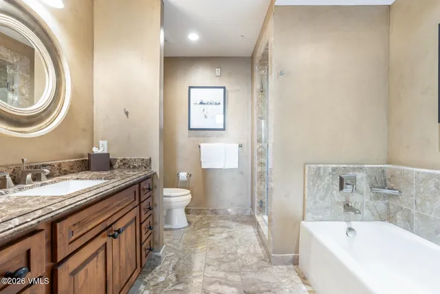 a bathroom with a granite countertop sink a toilet and a bathtub