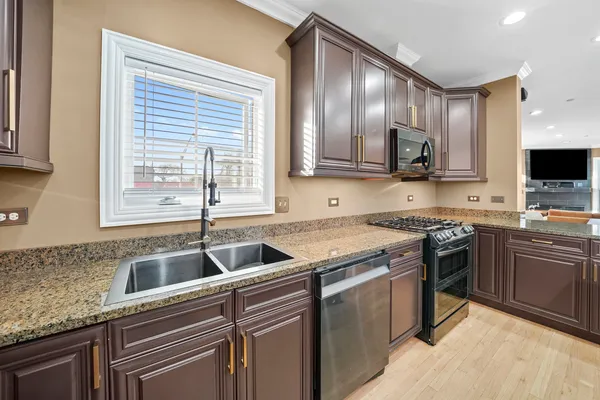 a kitchen with kitchen island granite countertop a sink stainless steel appliances and cabinets