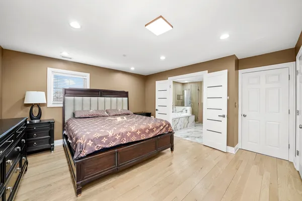 a spacious bedroom with a bed and wooden floor