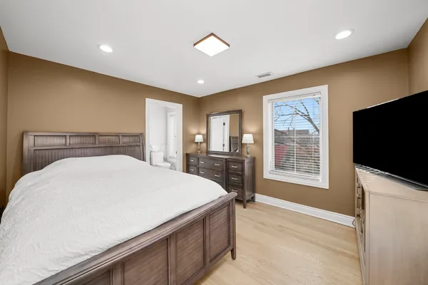 a bedroom with a large bed and a flat tv screen on dresser