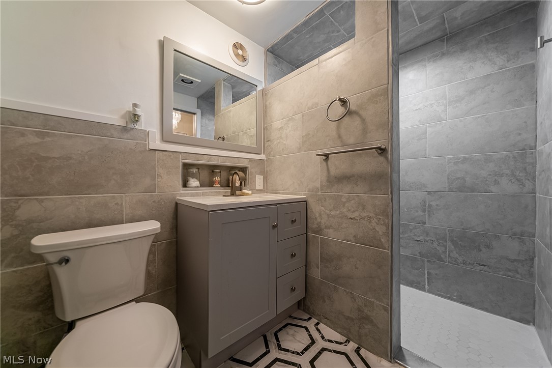 13800 Fairhill Road, Unit 306 Cleveland, OH 44120 - Photo 13 of 48 Updated en-suite bath off the primary suite featuring a tiled walk-in shower, modern vanity, stylish wainscoting, and contemporary tile finishes throughout.