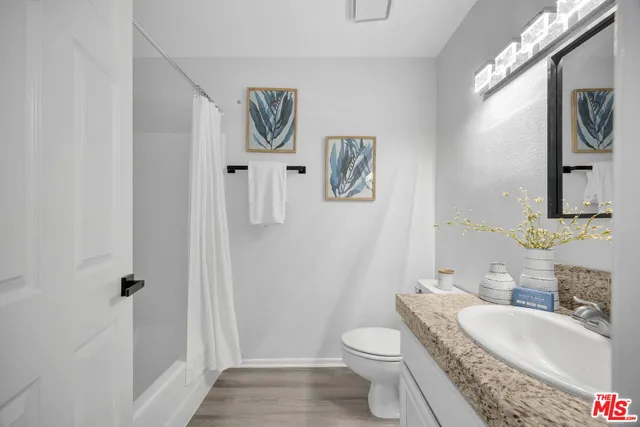 a bathroom with a granite countertop toilet and a sink