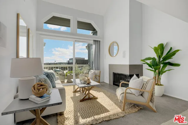 a living room with furniture a fireplace a potted plant and a window