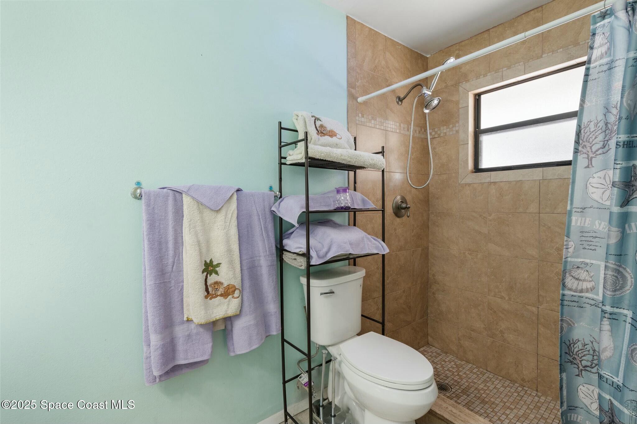 1550 Creel Road Northeast Palm Bay, FL 32905 - Photo 12 of 27 a white toilet sitting next to a bathroom sink and vanity